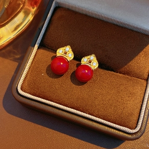 Macro shot of red floral stud earrings with gold plating and zircon in a jewelry box