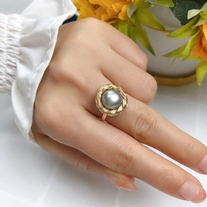 Elegant gold ring with a grey pearl and braided texture on a model's hand