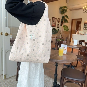 Lifestyle view of a pink quilted tote bag with floral bear pattern in a cozy cafe setting