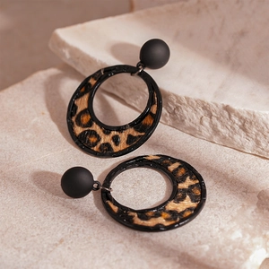 Detailed view of leopard print flocked round earrings on a beige textured stone background