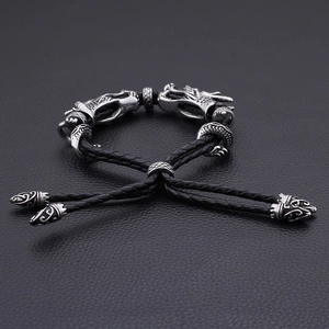 Détail des doubles breloques tête de dragon sur bracelet en cuir tressé pour hommes