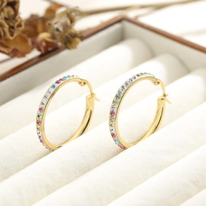 Detail of gold hoop earrings with multi-color crystals in a beige jewelry box