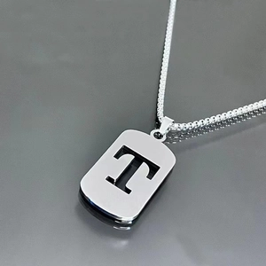Macro shot of silver titanium steel necklace featuring a hollow rectangular letter T pendant