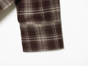 Close-up of classic dark brown plaid shirt cuff showing woven flannel fabric texture