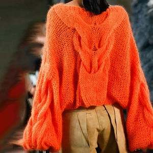 Detailed back view of orange cable knit sweater with loose lantern sleeves and thick texture