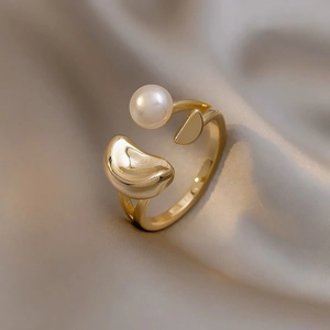 Macro detail of 18K gold plated bow ring with a lustrous white pearl on velvet