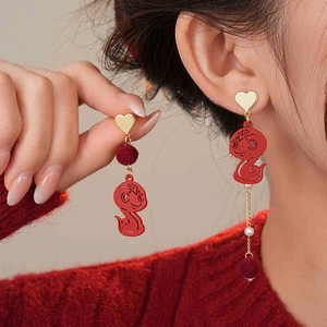 Detailed close-up of asymmetric Chinese New Year earrings with red snake and heart design