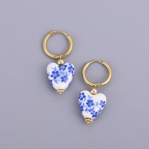 Detail of blue and white heart porcelain earrings with gold stainless steel hoops