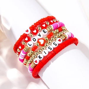 Macro shot of layered pink and red beaded bracelets with LOVE and KISS letter beads