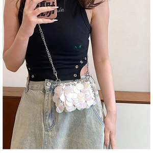 Mirror selfie showing a white sequin chain crossbody bag with a black cutout top