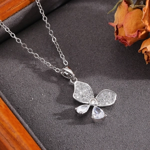 Detail of silver bow pendant with cubic zirconia on dark velvet jewelry display
