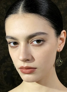 Detalle de pendientes retro de bronce con gema verde usados por una modelo
