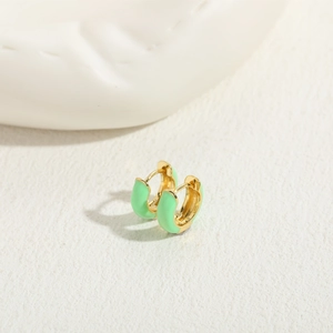 Detail of gold huggie earrings featuring light green enamel drip glaze and hidden clasp