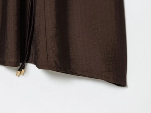 Détail du tissu marron foncé au lustre métallique avec embout doré sur les cordons