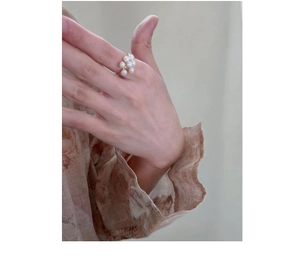 Close-up of golden ring featuring white pearl flower cluster on model finger