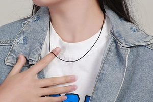 Detail of a minimalist black thin snake chain necklace worn on a model neckline