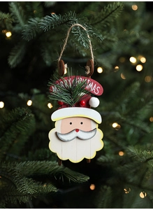 Detail of wooden Santa ornament with Merry Christmas banner on a lit Xmas tree