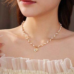 Detail of a pearl necklace featuring a gold star and moon pendant with small crystals