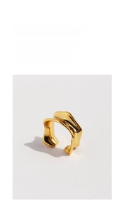 Macro detail of golden irregular wavy ring featuring polished metallic surface and open band