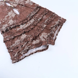 Detail view of deep brown floral print romper with ruffled layers and button neck design
