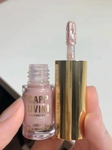 Close-up of pink glitter liquid eyeshadow applicator and bottle with golden lettering