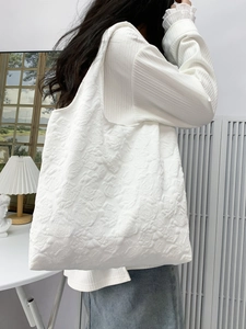Detail shot of white tote bag featuring embossed rose floral texture and jacquard fabric