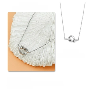 Macro view of polished silver knot pendant on a delicate chain necklace