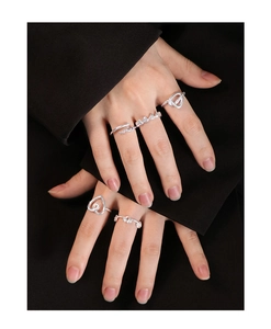 Detail shot of hollow heart silver rings stacked on fingers with a minimalist aesthetic