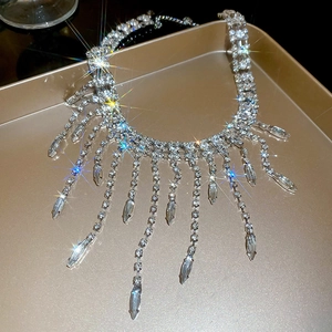 Macro detail of rhinestone fringe necklace with marquise pendant on golden tray