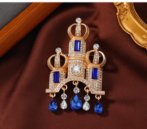 Macro view of vintage castle brooch with blue gemstones and hanging waterdrop charms