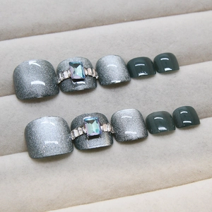 Silver cat eye and dark green press-on toenails set with rhinestone accents in a gray box