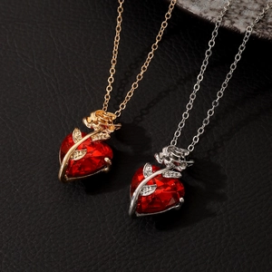 Detailed view of red heart pendants with gold and silver rose vines on dark leather