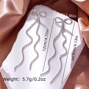 Detail of silver bow earrings with rhinestone tassels showing dimensions and sparkle