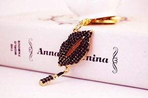Detailed shot of sparkling rhinestone red lips and lipstick keychain on a book cover