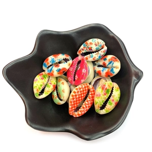 Colorful natural conch shells with floral prints and patterns in a black flower plate