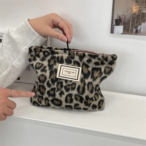 Detailed close-up of leopard print plush cosmetic bag with zipper and logo patch