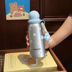 Detail of silver polka dot insulated bottle with a light blue spherical cap and floral charm