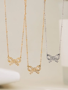 Detailed view of hollow bow pendants with shimmering pavé stones on beaded O-chains