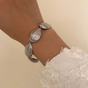 Close-up of a silver-toned textured shell teardrop link bracelet worn on a wrist
