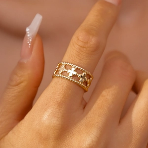 Detail of gold floral open cuff featuring intricate hollow petals and beaded edges