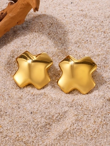 Gros plan détaillé de boucles d'oreilles géométriques dorées sur sable blanc
