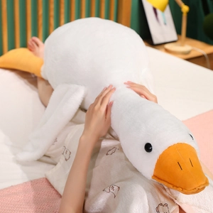 Detail shot of the large white goose plush toy's soft texture and orange beak on a bed