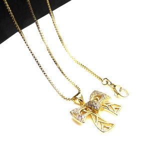 Close-up of golden bow pendant with micro-set zircons and a classic box chain necklace