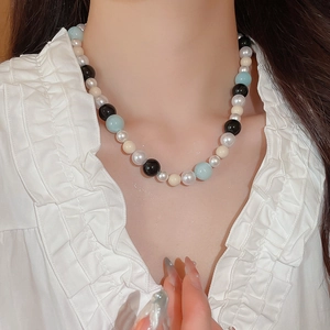 Detail of elegant mixed pearl and glass beaded necklace worn by a model in soft lighting