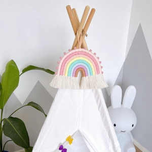 Detailed close-up of woven cotton rainbow wall hanging with soft pom-poms and tassels