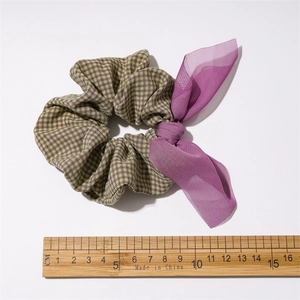 Detailed view of green and purple plaid scrunchie with sheer bow and size ruler