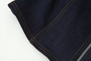 Gros plan sur veste en jean bleu foncé avec coutures contrastées et fermeture éclair en métal