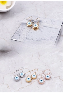 Détail de boucles d'oreilles Œil de Turquie en finitions or, argent et or rose