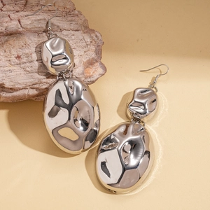 Modern irregular geometric silver earrings with hammered texture on a neutral background