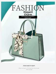 Detail of mint green cross-grain leather handbag with gold logo and printed silk scarf
